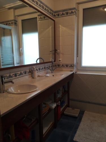 a bathroom with two sinks and a large mirror at Casa Cabarceno Piscina y Barbacoa in Bofetán
