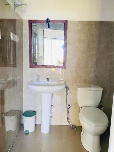 a bathroom with a sink and a toilet and a mirror at Anuradhapura Kingdom View Resort in Anuradhapura