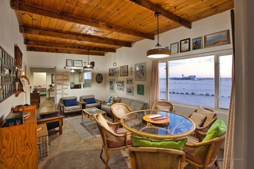 a living room with a table and chairs and the ocean at Wlotzkasbaken, Barefoot Self-catering in Wlotzkasbaken