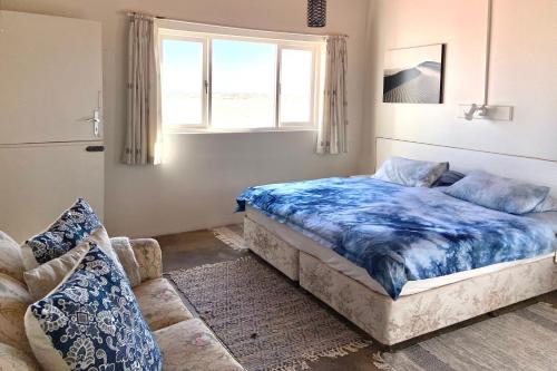 a bedroom with a bed and a window and a couch at Wlotzkasbaken, Barefoot Self-catering in Wlotzkasbaken