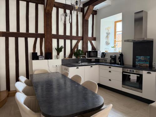 une cuisine avec une table noire et des armoires blanches dans l'établissement Maison de charme au cœur de Saint Valéry sur Somme, à Saint-Valery-sur-Somme