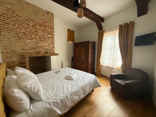 a bedroom with a bed and a chair and a brick wall at Maison de charme au cœur de Saint Valéry sur Somme in Saint-Valery-sur-Somme