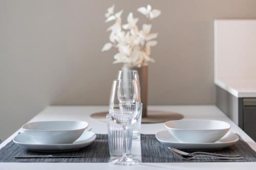 a table with two plates and a vase with flowers at Locarno Center - Free Parking, Netflix and WiFi in Locarno
