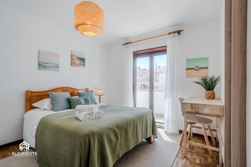 Un dormitorio con una cama y un escritorio y una ventana. en Azenha Beach House - Sea view with BBQ, en Santa Cruz