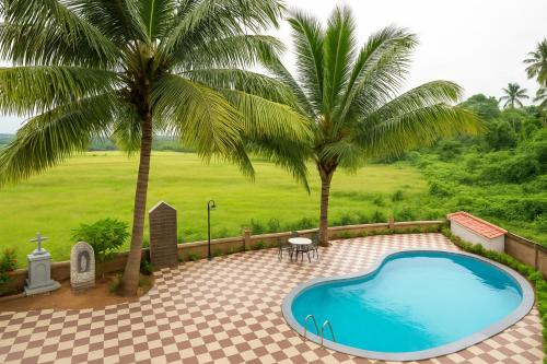 a swimming pool in a yard with two palm trees at Casa Da Village Calangute Goa in Calangute