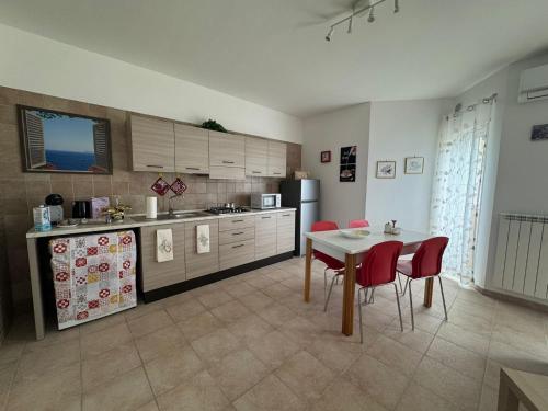 a kitchen with a table and some red chairs at A casa di Lorenza in Taranto