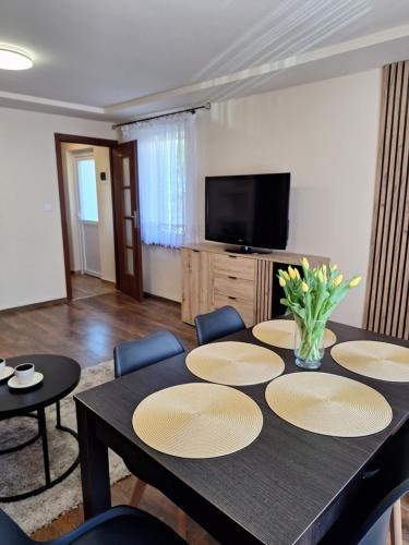 a dining room with a table and chairs and a television at Pensjonat Koral in Darłówko