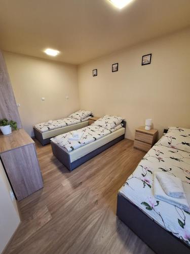 three beds in a room with wooden floors at Pensjonat Koral in Darłówko