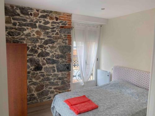 Un dormitorio con una cama y una pared de piedra. en Precioso piso 1 muy cerca de la playa de Salinas, en Piedras Blancas
