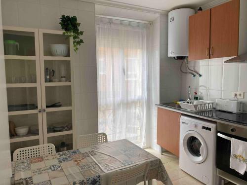 cocina con mesa y lavadora en Precioso piso 1 muy cerca de la playa de Salinas, en Piedras Blancas