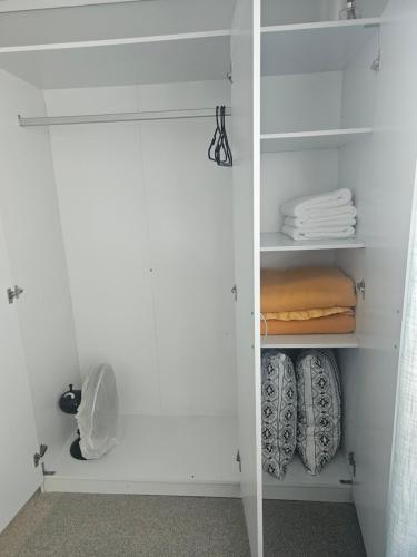 a white closet with white shelves and towels at A space of your own in Rotorua