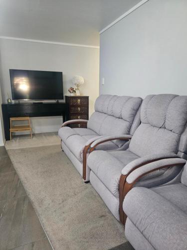a living room with two couches and a flat screen tv at A space of your own in Rotorua
