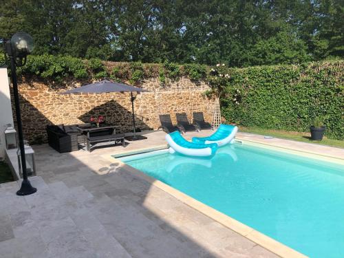 a swimming pool with two chairs and an umbrella at Villa MY le Mans in Saint-Saturnin