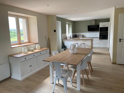 une cuisine et une salle à manger avec une table et des chaises en bois dans l'établissement Lovely Normandy Charmante maison de campagne, à La Bigne