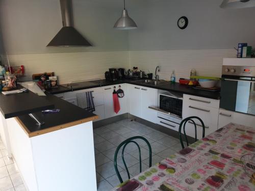 a kitchen with white cabinets and a table with a tableablish at Petite maison du samedi au samedi in Biscarrosse