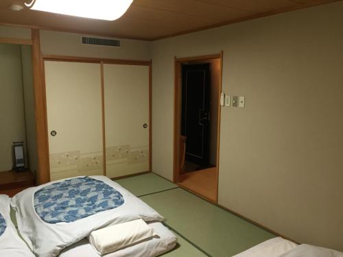 an empty room with a bed and a mirror at Hotel Crown Hills Kitami in Kitami