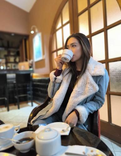 een vrouw aan een tafel die een kop koffie drinkt bij Hotel Tartar in Cajamarca