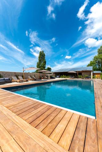 une piscine avec une terrasse en bois et un ciel bleu dans l'établissement Maisons H Normandie, à Cricquebœuf