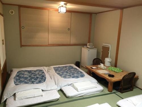 a room with two beds and a table and a cabinet at Hotel Crown Hills Kitami in Kitami