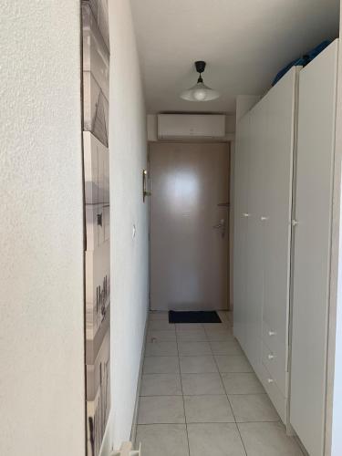 un couloir avec une porte et un sol carrelé dans l'établissement Spacieux studio vue mer sur le port, à Frontignan