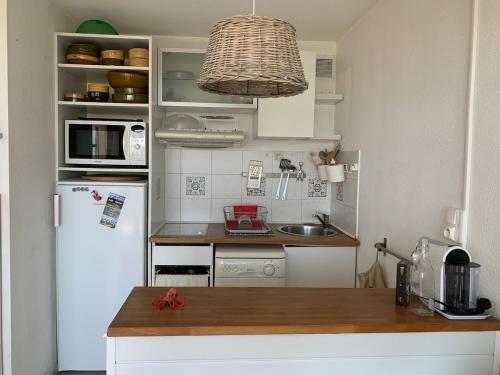La cuisine est équipée d'un réfrigérateur blanc et d'un four micro-ondes. dans l'établissement Spacieux studio vue mer sur le port, à Frontignan