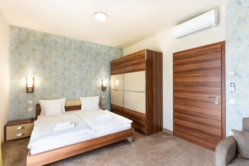 a bedroom with a white bed and a wooden cabinet at B&B Lajta Park in Mosonmagyaróvár