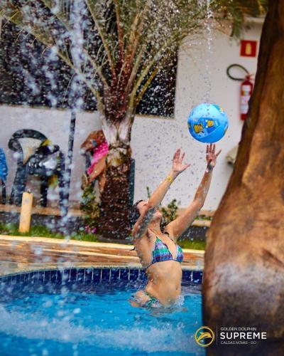 a woman playing with a ball in a swimming pool at Golden Dolphin Grand Hotel piscinas 24 hs MP in Caldas Novas