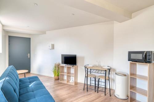 un salon avec un canapé bleu et une télévision dans l'établissement Paisible Studio- CNPE Centrale du bugey, à Loyettes