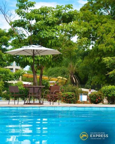 a table with an umbrella next to a swimming pool at Golden Dolphin Grand Hotel piscinas 24 hs MP in Caldas Novas