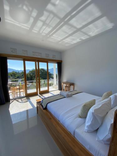 a bedroom with a large bed and a balcony at Batur Pyramid Guesthouse in Kintamani