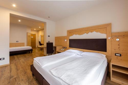 a bedroom with a large white bed and a desk at Park Hotel Avisio in Soraga