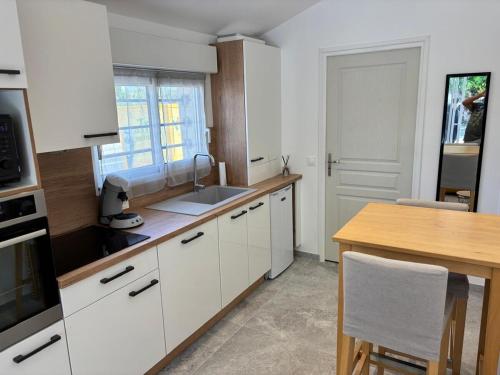 a kitchen with white cabinets and a wooden table at Studio L'Essentiel in Istres