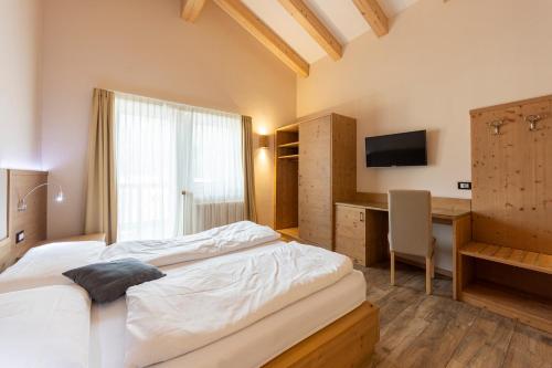 a bedroom with a bed and a desk and a television at Park Hotel Avisio in Soraga