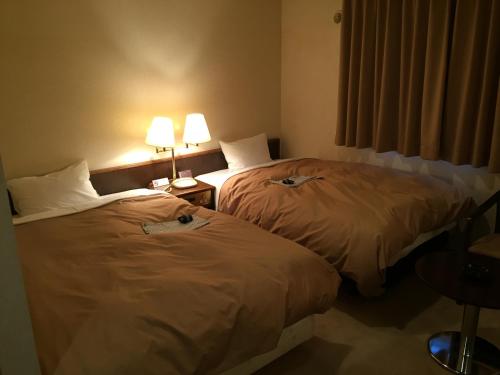 two beds sitting next to each other in a hotel room at Hotel Crown Hills Kitami in Kitami