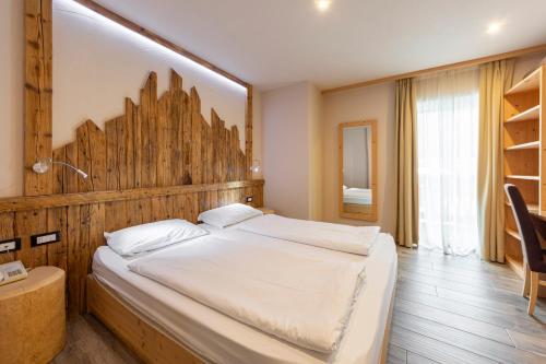 a bedroom with a large bed with a wooden headboard at Park Hotel Avisio in Soraga