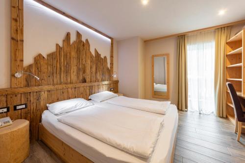 a bedroom with a large bed with a wooden headboard at Park Hotel Avisio in Soraga