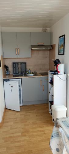  La cuisine est équipée de placards blancs et d'un réfrigérateur. dans l'établissement Bel appartement T2 150m plage et tous commerces, à Villers-sur-Mer
