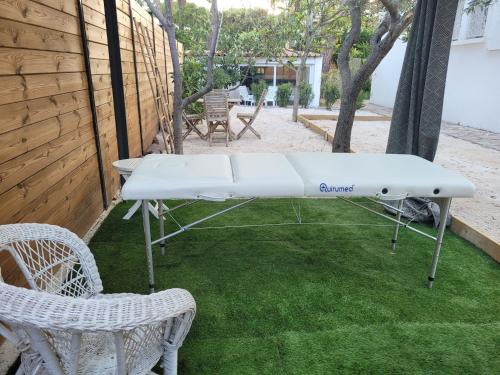a white ping pong table on a lawn with two chairs at Villa Rasoa in Cap d'Agde
