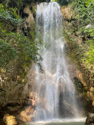 a man sitting in front of a waterfall at Quế Homestay in Hòa Bình