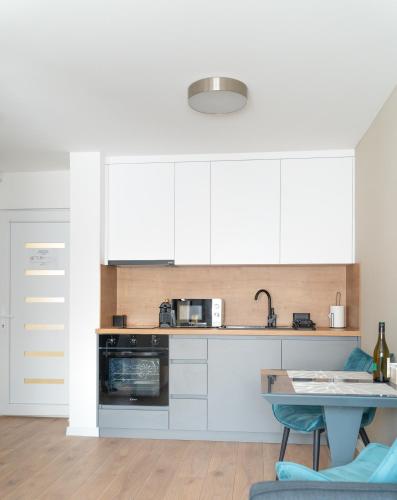a kitchen with white cabinets and a table at REMZ Apartments & Wellness in Dorog