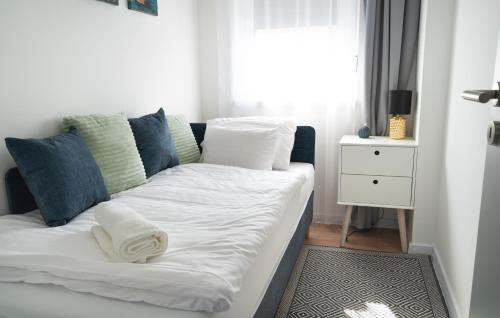 a bed with white sheets and blue pillows in a room at REMZ Apartments & Wellness in Dorog