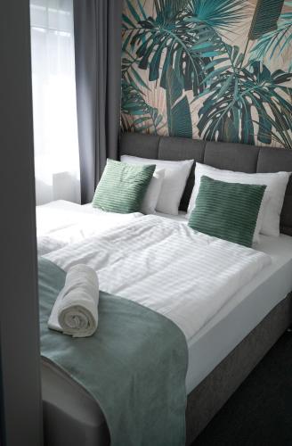 a large bed with white sheets and green pillows at REMZ Apartments & Wellness in Dorog