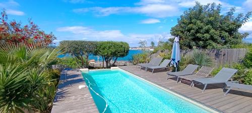 une piscine avec des chaises et un parasol et l'océan dans l'établissement Confortable Villa en bord de Mer avec piscine, à Bandol