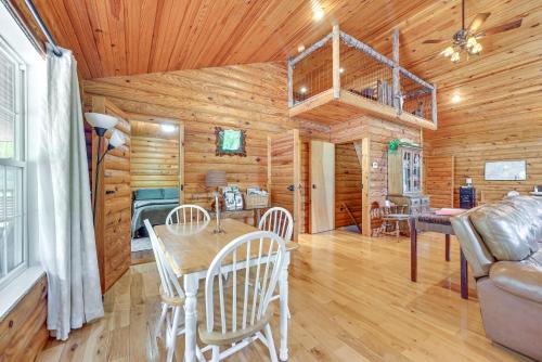 a dining room and living room in a log cabin at Woodsy Kentucky Escape with Game Room and Lake Access! in Burnside