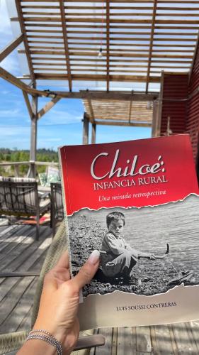 a person holding a book in their hand at Casa Chiloe in Penanes Bajo