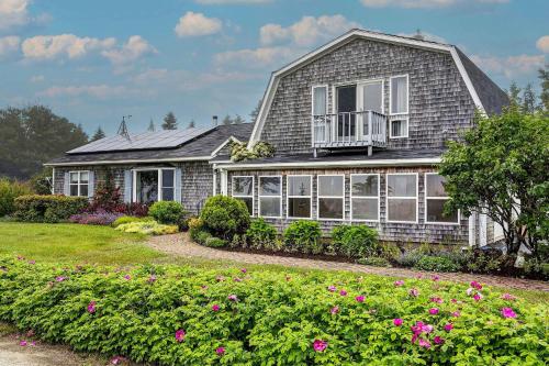 a house with a balcony and flowers in the yard at Bay Views Peaceful Acadia National Park Getaway! in Steuben