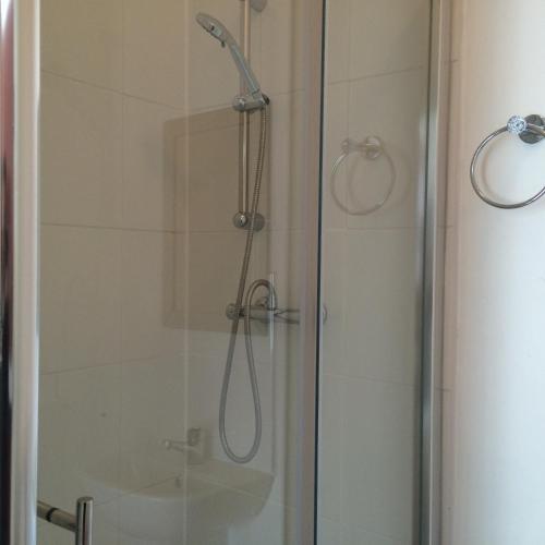a shower with a glass door with a shower head at Metro Star in London
