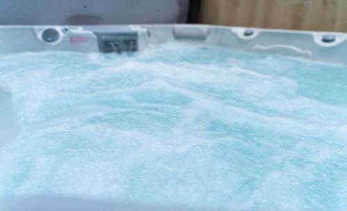 a bath tub filled with turquoise colored water at REMZ Apartments & Wellness in Dorog