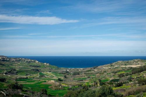 a view of the ocean from a hill at The Valley Collection - Suite A21 in Xagħra
