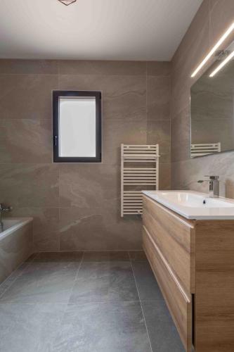 une salle de bain avec une baignoire, un lavabo et un miroir dans l'établissement La Fontaine de Mayol, à Sablet